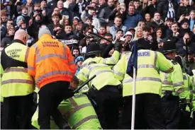  ?? ?? Out of control: police rush towards West Brom fans to prevent a pitch invasion
