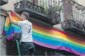  ?? ASSOCIATED PRESS PHOTOS ?? A man hangs a rainbow flag on a building in the Chueca district, a popular area for the gay community in Madrid, as Spain’s capital geared up to host the 10-day WorldPride 2017, which started on Friday.