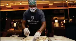  ??  ?? Sharon Holm, a volunteer from Food Rescue US, prepares cold cuts for sandwiches at Marcus Samuelsson’s Red Rooster Restaurant during the new coronaviru­s pandemic.