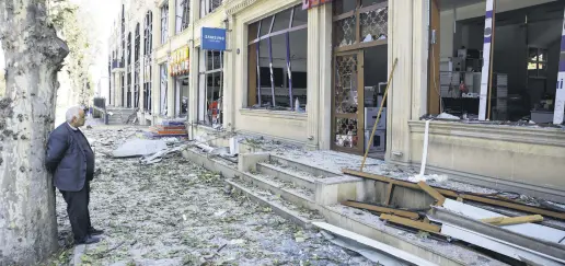  ??  ?? A shop owner stands in front of his store at a blast site from an Armenian rocket in the city of Ganja, Azerbaijan, Oct. 11, 2020.