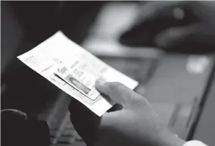  ?? Associated Press file photo ?? n An election official checks a voter’s photo identifica­tion at an early voting polling site on Feb. 26, 2014, in Austin. A federal judge Wednesday again threw out Texas’ voter ID requiremen­ts that she previously compared to a “poll tax” on minorities,...