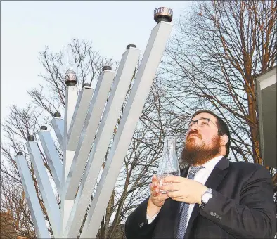 ?? Mike Lauterborn / For Hearst Connecticu­t Media ?? Rabbi Shlame Landa of Chabad of Fairfield prepares to light the first candle on the menorah on Sherman Green in 2015.