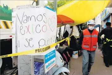  ??  ?? “LET’S GO Mexico. Yes we can!” says a sign on a phone near where families wait for news from search efforts.