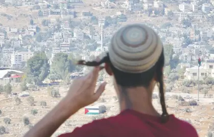  ?? (Marc Israel Sellem/The Jerusalem Post) ?? A YOUNG MAN in the illegal Evyatar outpost looks out at the Palestinia­n village of Beita yesterday.