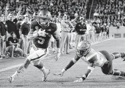  ??  ?? Texas A&amp;M’s Trayveon Williams, who rushed for 167 yards, slips by UAB’s Chris Woolbright for the first of his two touchdowns. Michael Wyke / Associated Press