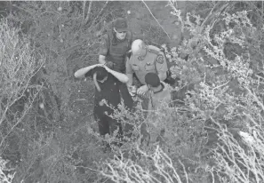  ?? JOHN MOORE/GETTY IMAGES ?? A state trooper and a Border Patrol agent detain immigrants in Texas.