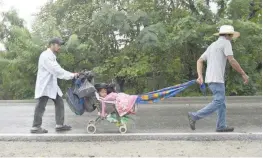  ?? — AFP ?? Honduran migrants push a stroller with a baby as they take part in a caravan towards the United States in Zacapa, 145 km east of Guatemala City. A migrant caravan set out on October 13 from the country and was headed north on the long journey through Guatemala and Mexico to the US border. President Donald Trump warned Honduras he will cut millions of dollars in aid if the group of about 2,000 migrants is allowed to reach the United States.