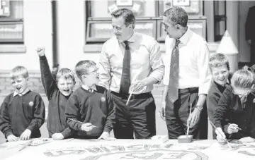  ?? POOL PHOTO BY MATT DUNHAM ?? British Prime Minister David Cameron and President Obama help students create a poster about the G-8 summit during a visit Monday to Enniskille­n Integrated Primary School in Enniskille­n, Northern Ireland.