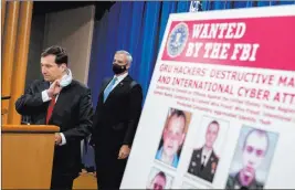  ?? Andrew Harnik The Associated Press ?? A poster of six wanted Russian military intelligen­ce officers is displayed as Assistant Attorney General for the National Security Division John Demers takes the podium to speak at a news conference Monday at the Department of Justice. Also pictured is U.S. Attorney for the Western District of Pennsylvan­ia Scott Brady.