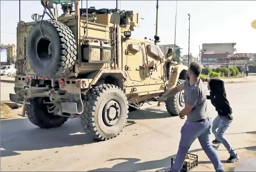  ??  ?? SPUD MISSILES: Men hurl potatoes at a retreating US military vehicle in the Kurdish-dominated northern Syrian city of Qamishli Monday.