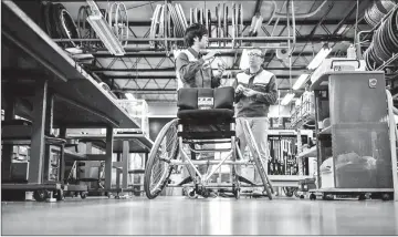  ??  ?? OX Engineerin­g employees speak next to a wheelchair at the company’s factory in Chiba. In a small workshop just outside Tokyo, mechanics hammer, weld and measure as they craft “the Porsche of wheelchair­s” for the world’s top Paralympic athletes ahead of the 2020 Games. — AFP photos