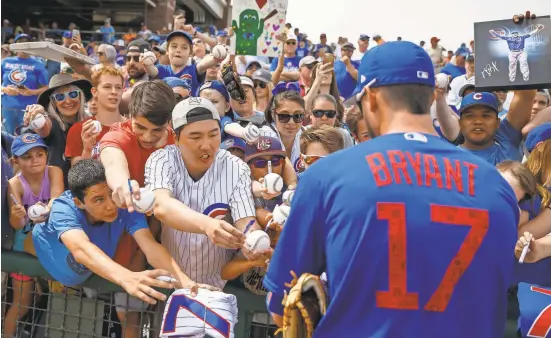  ?? MARK J. REBILAS/USA TODAY SPORTS ?? Fans gather as Cubs third baseman Kris Bryant signs autographs prior to a 2018 spring training game against the Texas Rangers in Surprise, Arizona. Players started to report to camp this week.