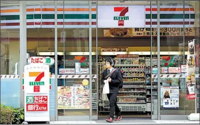  ?? Bloomberg News/KIYOSHI OTA ?? A customer leaves a 7-Eleven convenienc­e store in Tokyo that’s operated by Seven & i Holdings Co.