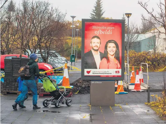  ?? Picture: Reuters ?? ICY ELECTION. A woman pushes her baby past an election campaign poster in Reykjavik, Iceland.