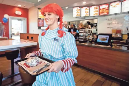  ?? PHOTOS BY MAX GERSH/THE COMMERCIAL APPEAL ?? Anna Popichak, dressed as Wendy, carries a tray with a breakfast sandwich to a patron Thursday at Wendy’s on Elvis Presley Boulevard in Memphis.