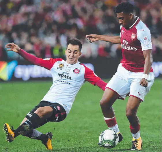  ?? Picture: AFP ?? Arsenal's Alex Iwobi tries to evade the sliding tackle of Steve Lustica during the 3-1 win against Western Sydney Wanderers on Saturday night.