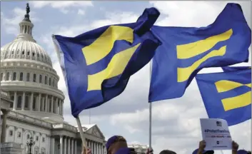  ??  ?? In this July 26 file photo, people with the Human Rights Campaign hold up “equality flags” during an event on Capitol Hill in Washington, in support of transgende­r members of the military. Officials say the Pentagon expects soon to ban transgende­r...