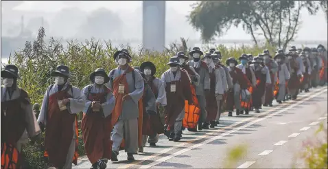  ?? (AP/Lee Jin-man) ?? Buddhist monks and believers walk along a stream in Seoul, South Korea. About 100 monks and followers marched the 310-mile pilgrimage to pray for the country to overcome the coronaviru­s.