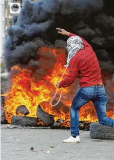  ?? Foto: Abbas Momani, afp ?? Ein Palästinen­ser wirft in Ramallah Reifen in eine brennende Barrikade: Der Nahost Konflikt rückt nach oben auf die Liste aktueller Krisenherd­e.