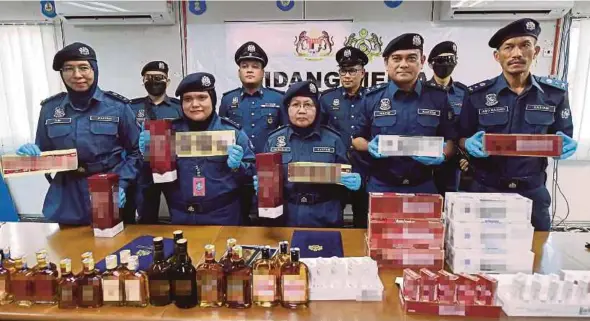  ?? BERNAMA PIC ?? Central Zone Customs Department deputy director Norlela Ismail (centre) showing the seized counterfei­t alcoholic beverages and illicit cigarettes at the department’s marine base in Klang yesterday.