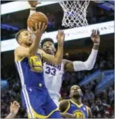  ?? CHRIS SZAGOLA — THE ASSOCIATED PRESS ?? Golden State’s Stephen Curry, left, goes up for the shot with the 76ers’ Robert Covington defending early on in the Sixers’ loss to the defending champion Warriors Saturday night.