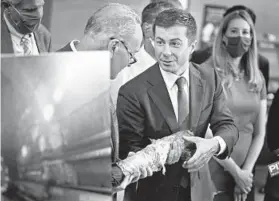  ?? SETH WENIG/AP ?? Secretary of Transporta­tion Pete Buttigieg, right, holds a decaying piece of a rail tunnel during a June news conference in New York.