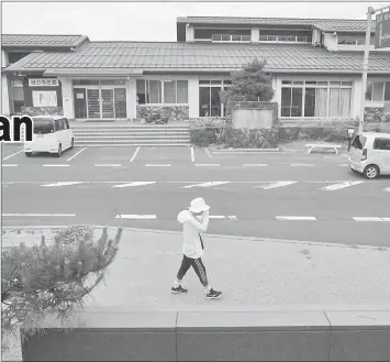  ??  ?? A woman walks on a street as a car (right) used for a sharing service supported by rber drives past in hyotangoK