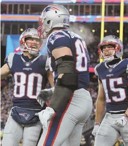  ?? STAFF PHOTO BY NANCY LANE ?? CATCH ALL: Rob Gronkowski (center) is congratula­ted by Danny Amendola (80) and Chris Hogan after his fourth-quarter touchdown reception in the Patriots’ 35-14 win against the Titans last night.