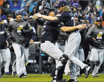  ?? John Leyba ?? The Associated Press Brewers catcher Erik Kratz and reliever Josh Hader hug as their teammates race to join them in celebratin­g Milwaukee’s Nlds-clinching 6-0 win over the Rockies on Sunday at Coors Field. Kratz had three hits.