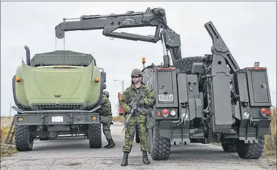  ?? CHRISTIAN ROACH/CAPE BRETON POST ?? A reserve service member stands guard as other troops fix an engine of a large truck during the exercise “Trench Sustain” at the old Radar Base on Saturday.