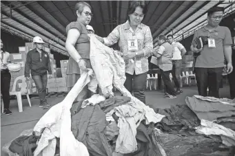  ??  ?? SHIPMENT DONATED – Some of the used clothing and blankets from Thailand are inspected by Customs District Collector Evelyn Cruz and Asst. Regional Director Grace Subong at the Cebu Port’s container yard. (Juan Carlo de Vela)