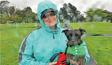  ??  ?? Even on a miserable wet day, Val Jenness enjoys walking Teddy in Avalon Park. Walking helps alleviate her back pain but Hutt City Council rules effectivel­y stop her from accessing the park.