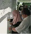  ??  ?? 三蘇（右起）及旺阿茲莎在布條上簽­名，緬懷故友。