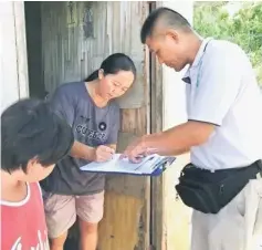  ??  ?? Chai fills out a form during a recent visit by Wan when he delivered food aid to the family.