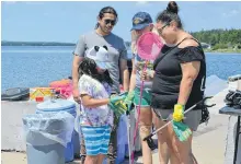  ?? ARDELLE REYNOLDS • CAPE BRETON POST ?? Seven-year-old Maxine Doucette puts on gloves to pick up garbage on the shoreline in Potlotek First Nation on Monday.