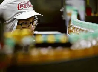  ?? Shizuo Kambayashi - 17.nov.16/Associated ?? Funcionári­o da Coca-Cola no Japão, mercado em que a empresa lançará bebida alcoólica