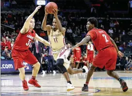  ?? ABBIE PARR / GETTY IMAGES ?? Florida State’s Braian Angola drives between Louisville’s Darius Perry (2) and Ryan McMahon in an ACC Tournament game Wednesday. “We weren’t quite as sharp as we needed to be,” says FSU coach Leonard Hamilton about the loss.