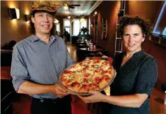  ?? The Sentinel-Record/Richard Rasmussen ?? ■ SQZBX Brewery & Pizza Joint owners Zac Smith, left, and Cheryl Roorda display one of their pizzas on Wednesday.