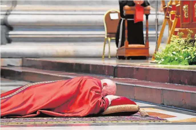  ??  ?? El Santo Padre se postra en los oficios del Viernes Santo celebrados en el interior de la basílica de San Pedro en el Vaticano