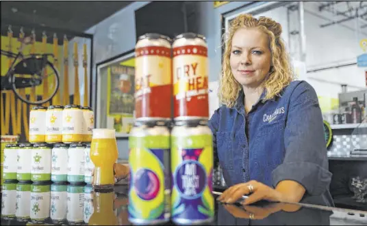  ?? Elizabeth Page Brumley Las Vegas Review-Journal @EliPagePho­to ?? CraftHaus co-owner Wyndee Forrest shows craft beer in cans, which cost more because of the change in import tariffs.