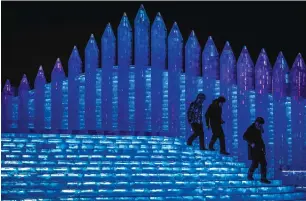  ??  ?? &lt;&lt; Visitors walk around ice sculptures illuminate­d by coloured lights. —