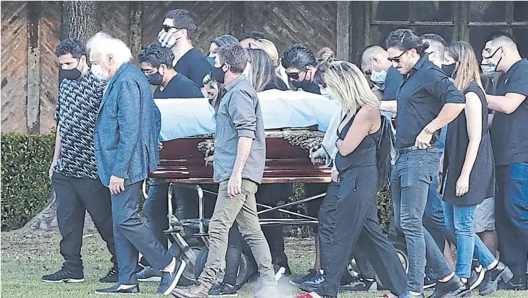  ??  ?? Guillermo Coppola abre la fila y cierra Claudia Villafañe: amigos y familiares trasladan el féretro de Maradona al llegar al cementerio de Bella Vista