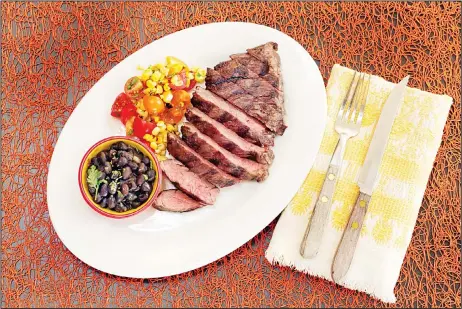  ??  ?? This Aug 4 photo shows skirt steak with beer-braised black beans and corn salsa, styled by Sarah Abrams, displayed at the Institute of Culinary Education in
New York. (AP)