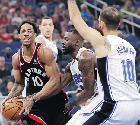  ??  ?? Toronto forward DeMar DeRozan looks for an outlet with Orlando’s Jonathon Simmons, centre, reaching for the ball and Evan Fournier protecting the rim during Wednesday’s 117-104 Raptors victory in Orlando. DeRozan led all scorers with 21 points. JOHN...