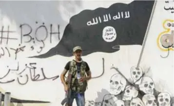  ?? |GETTY IMAGES ?? Un combatient­e de la coalición rebelde siria frente a un mural del Estado Islámico en Raqqa.