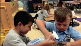  ?? / Contribute­d ?? From left, Jacob Ortiz and Maddox Cutshall prepare their seeds for the class growing experiment.