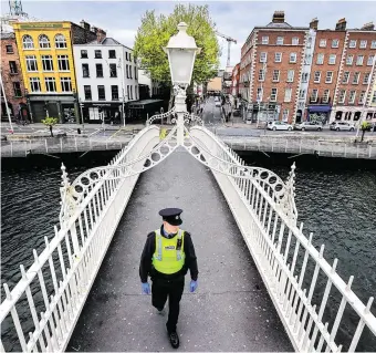  ?? PHOTO: GERRY MOONEY ?? Quiet:
A garda patrols a deserted Dublin city centre during the lockdown.