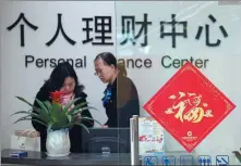  ?? XU JINBO / FOR CHINA DAILY ?? A financial manager (right) talks to a client at a State-owned commercial bank in Hai’an, Jiangsu province.