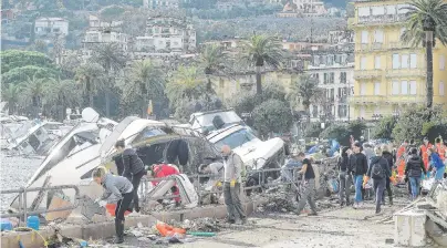  ?? PHOTOS: REUTERS ?? Aftermath . . . People help to remove debris around destroyed yachts on the shore after high winds and a powerful sea storm in Rapallo, Italy, yesterday.