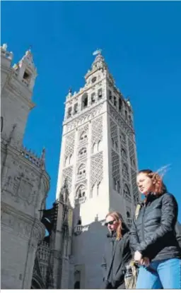  ??  ?? Dos jóvenes pasan ante la Giralda, cuya cara sur está ya libre del andamio.